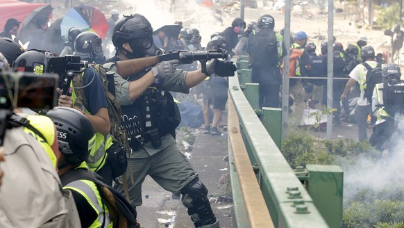 A police officer prepares to fire tear gas canisters during a clash with protesters near the Hong Kong Polytechnic University in Hong Kong, Monday, Nov. 18, 2019. (AP Photo/Achmad Ibrahim)