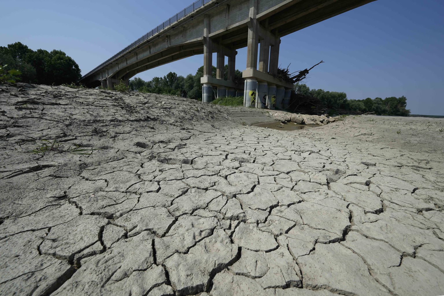 FILE - Dry cracked land is visible under a bridge in Boretto on the bed of the Po river, Italy, Wednesday, June 15, 2022. The mayor of Milan signed an ordinance Saturday, June 25, 2022, turning off pu ...