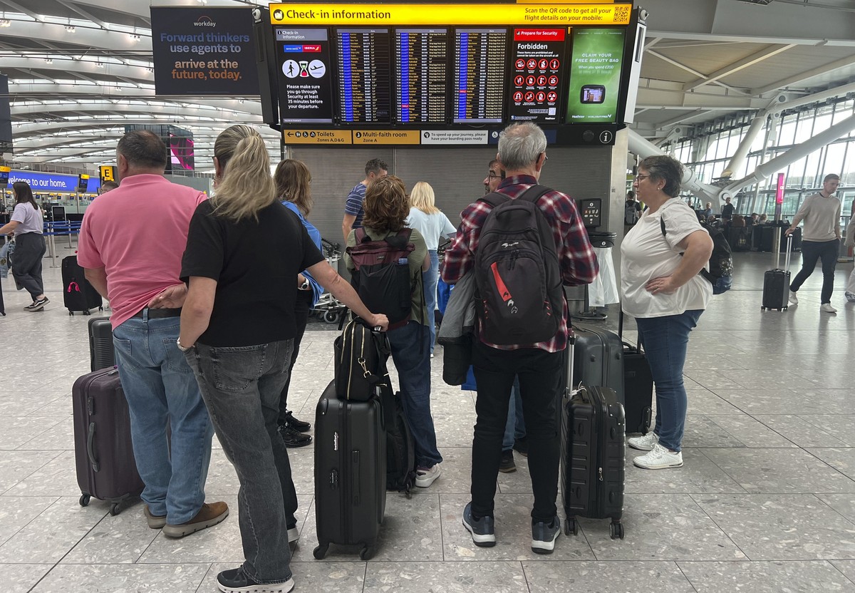People at T5 London Heathrow Airport look at the boards after flights were delayed and cancelled at airports including Heathrow after an alleged cyber attack targeted a service provider for check-in a ...