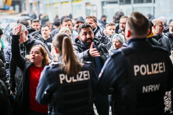 Aufgebrachte Demonstranten verlangen Zutritt zur von einem Polizei-Kordon abgesicherten Sparkassenfiliale.