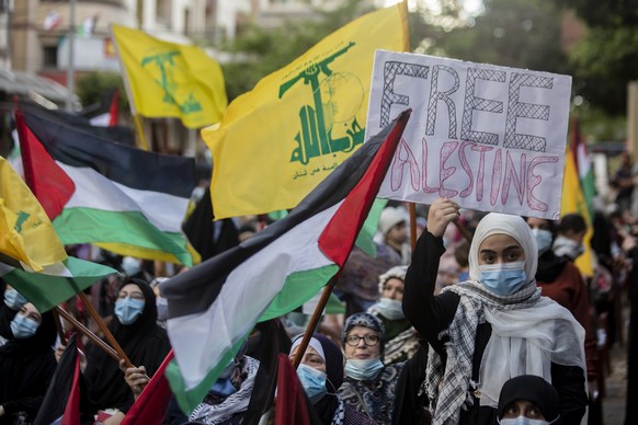 Lebanese and Palestinians shout slogans and wave flags, during a rally organized by Lebanon&#039;s militant Hezbollah group to express solidarity with the Palestinian people, in the southern suburb of ...