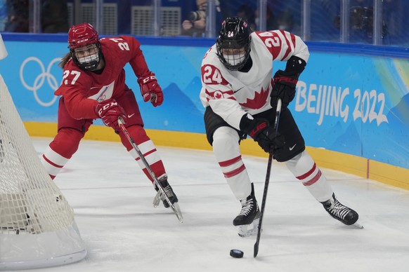 Canada&#039;s Natalie Spooner (24) and Russian Olympic Committee&#039;s Veronika Korzhakova (27) wear COVID masks as they play a preliminary round women&#039;s hockey game at the 2022 Winter Olympics, ...