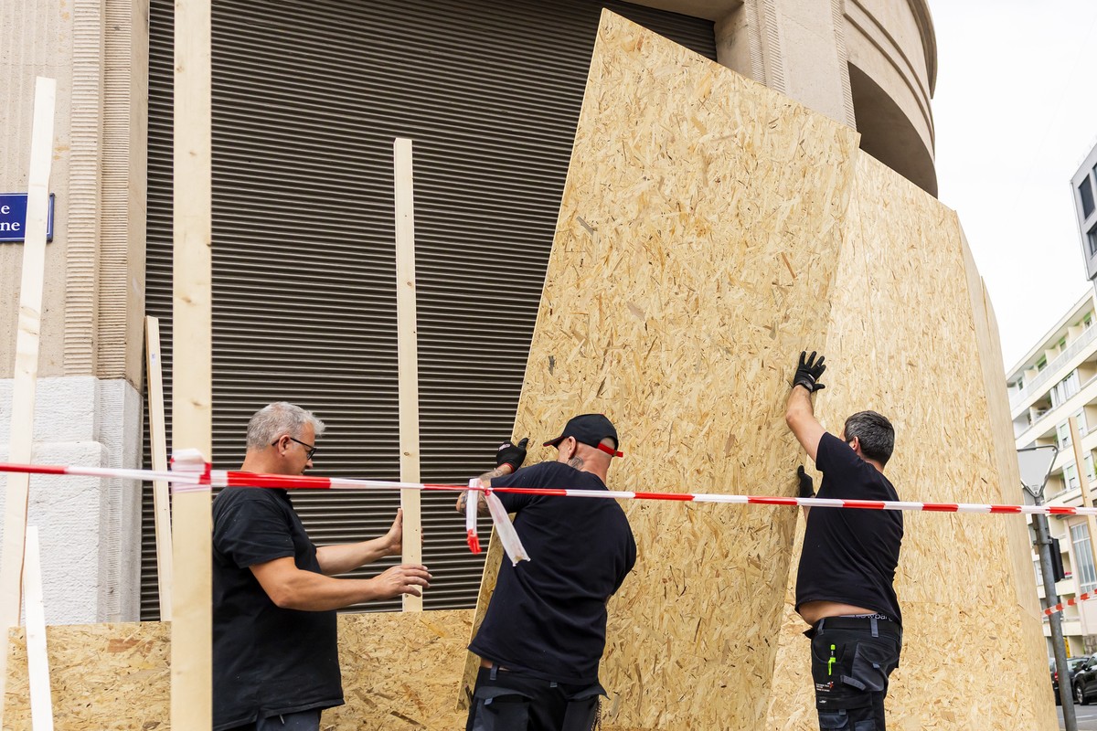 Des ouvriers installent des planches de bois devant les vitrines d'un etablissement pour le proteger d'eventuelles degradations de la part de manifestants durant la manifestation NoG7 liee a ...