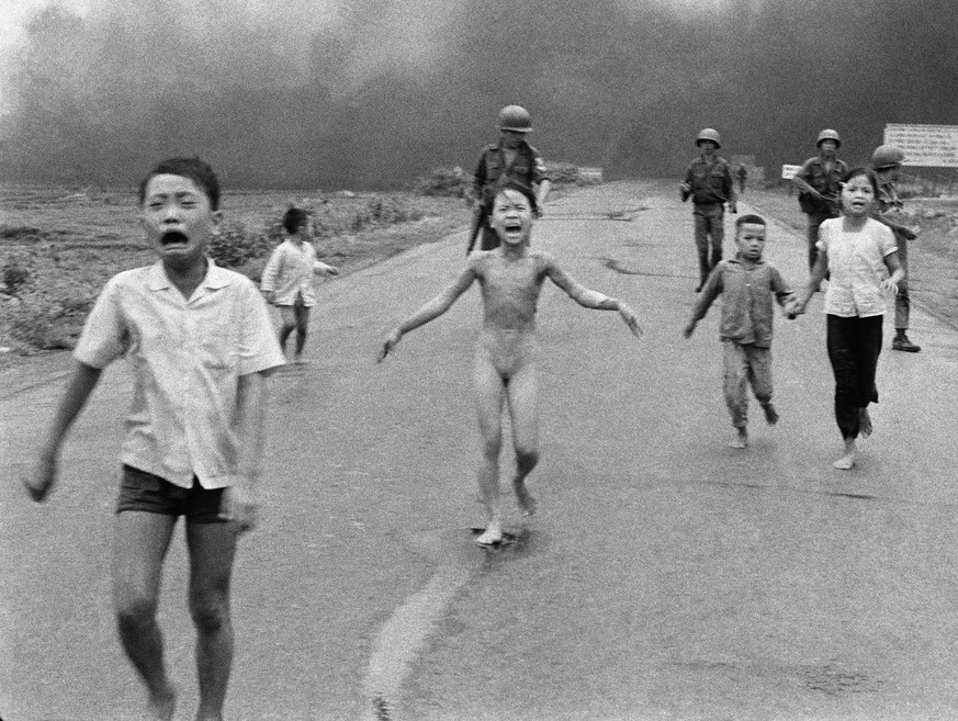 South Vietnamese forces follow after terrified children, including 9-year-old Kim Phuc, center, as they run down Route 1 near Trang Bang after an aerial napalm attack on suspected Viet Cong hiding pla ...