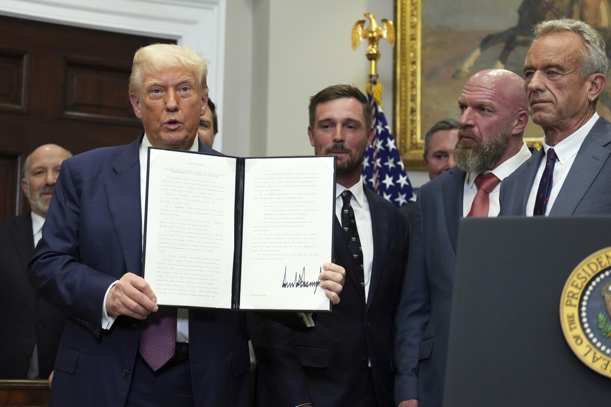 President Donald Trump holds up a signed executive order restarting the Presidential Fitness Test in public schools as Commerce Secretary Howard Lutnick, from left, professional golfer Bryson DeChambe ...