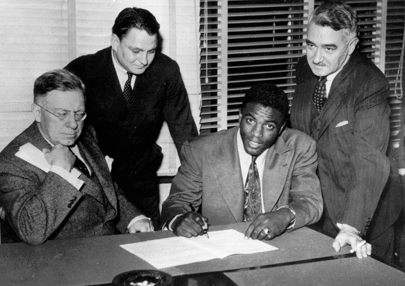 FILE - In this Oct. 23, 1945, file photo, Jackie Robinson, first Negro player in the major leagues, signs with the Montreal Royals in Montreal. From left are: Royals president Hector Racine, Branch Ri ...