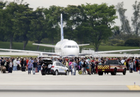 People stand on the tarmac at the Fort Lauderdale-Hollywood International Airport after a lone shooter opened fire inside the terminal, Friday, Jan. 6, 2017, in Fort Lauderdale, Fla. A gunman opened f ...