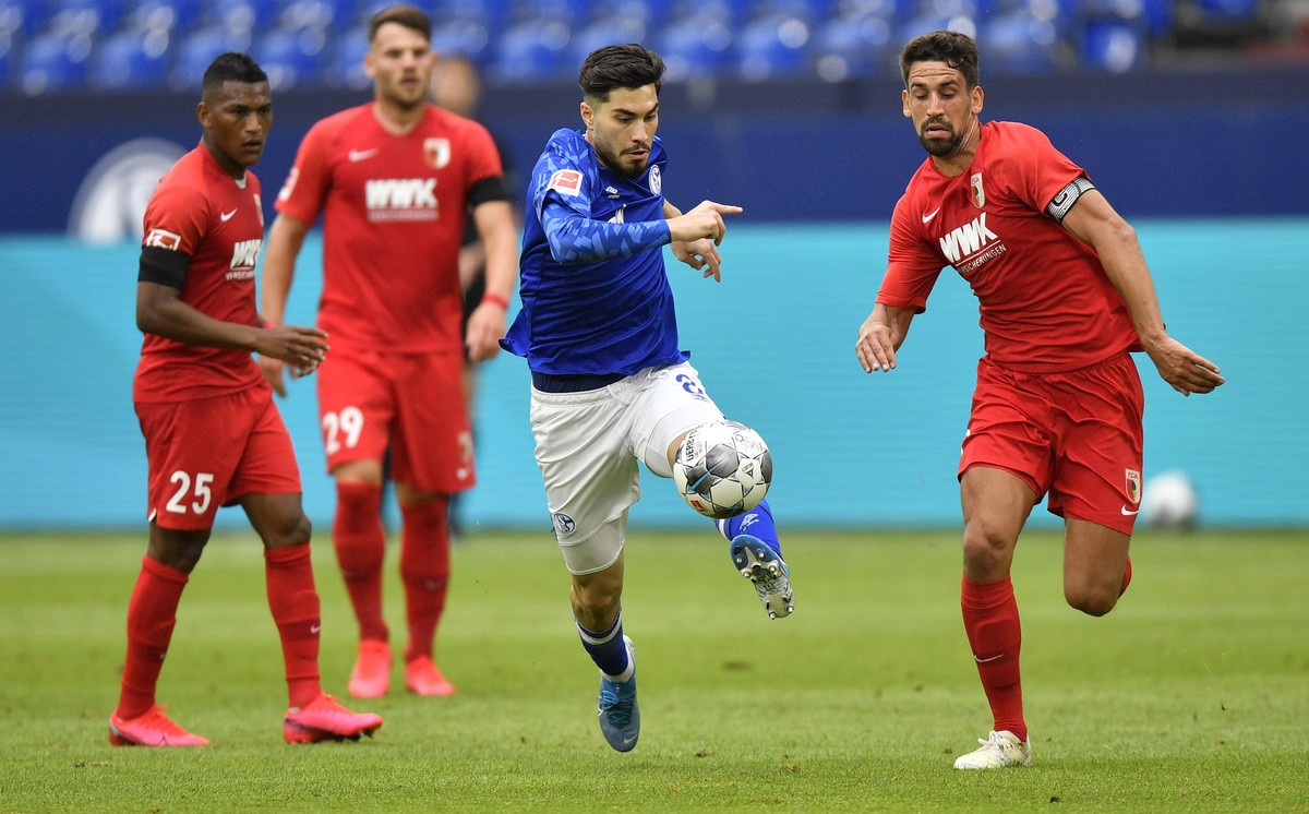 Schalke's Suat Serdar, second right, kicks the ball by Augsburg's Rani Khedira, right, during the German Bundesliga soccer match between FC Schalke 04 and FC Augsburg at the Veltins-Arena in ...