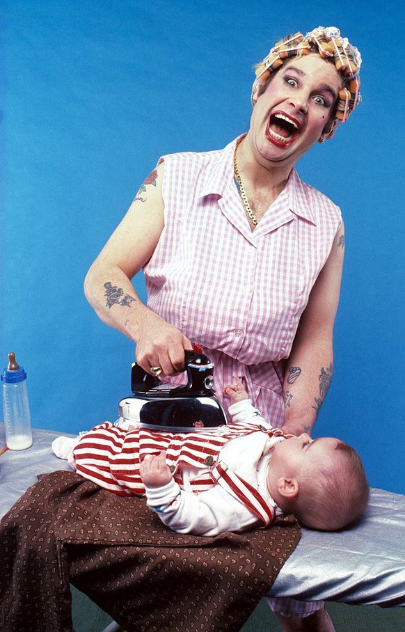 A portrait of Ozzy Osbourne, dressed as a 1950s housewife, ironing his daughter Aimee, New York, c1983. (Photo by Mark Weiss/Getty Images)