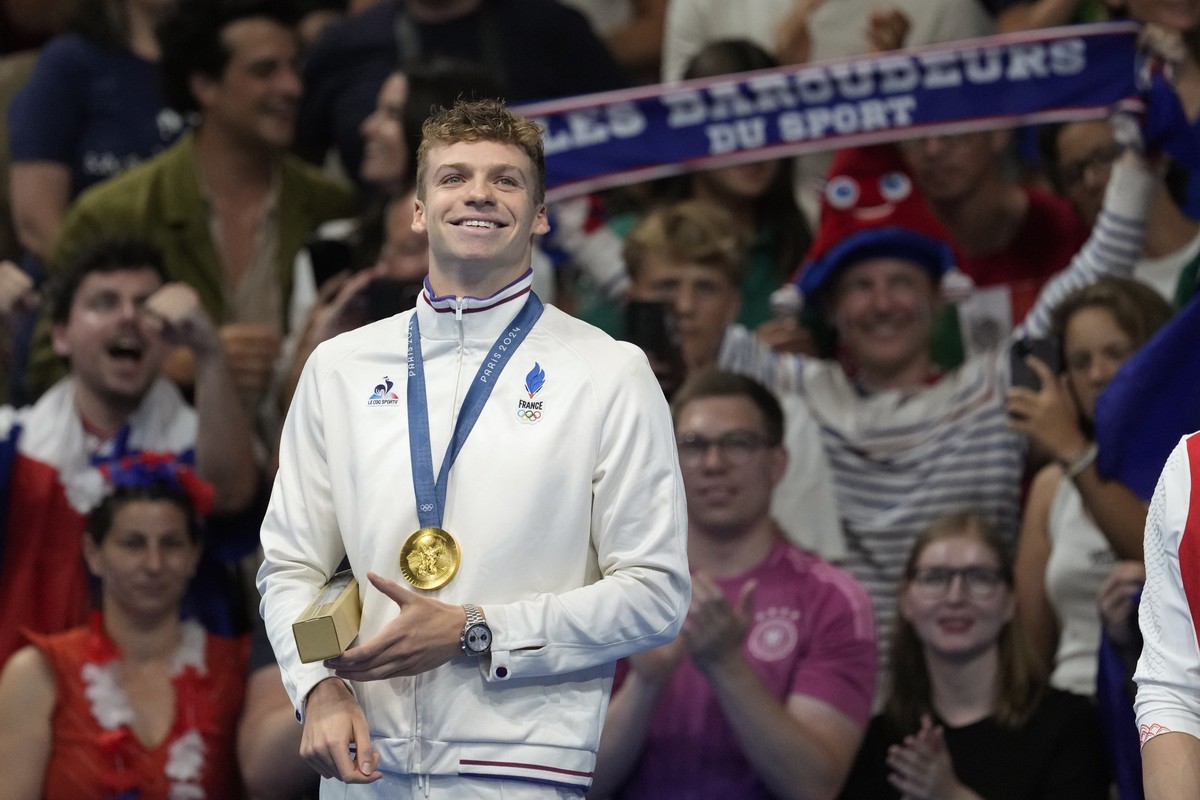 Leon Marchand of France, reacts as he stands on the podium after receiving his gold medal for the men's 200-meter individual medley final at the 2024 Summer Olympics, Friday, Aug. 2, 2024, in Nan ...