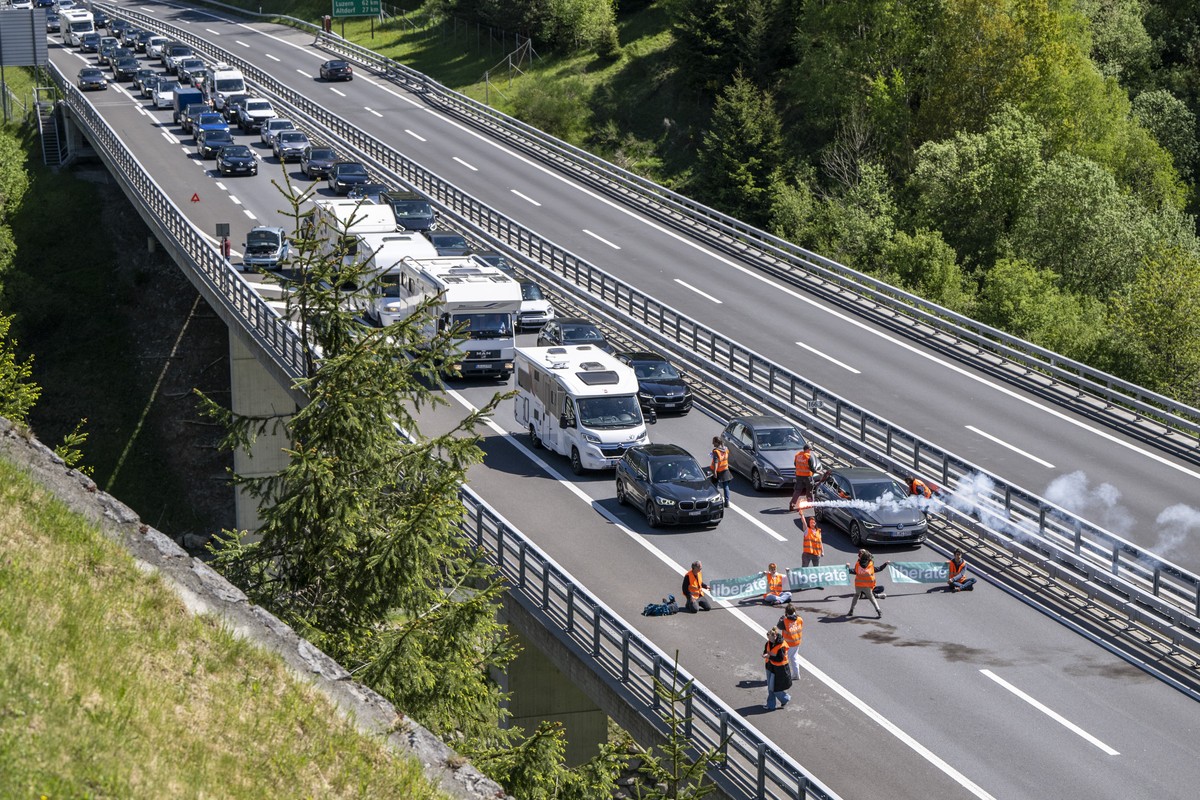 Aktivisten von "Renovate Switzerland" protestieren vor dem Gotthard Tunnel bei Goeschenen im Kanton Uri, weahrend dem sich der Auffahrt Reiseverkehr vor dem Gotthard Nordportal auf mehrere K ...
