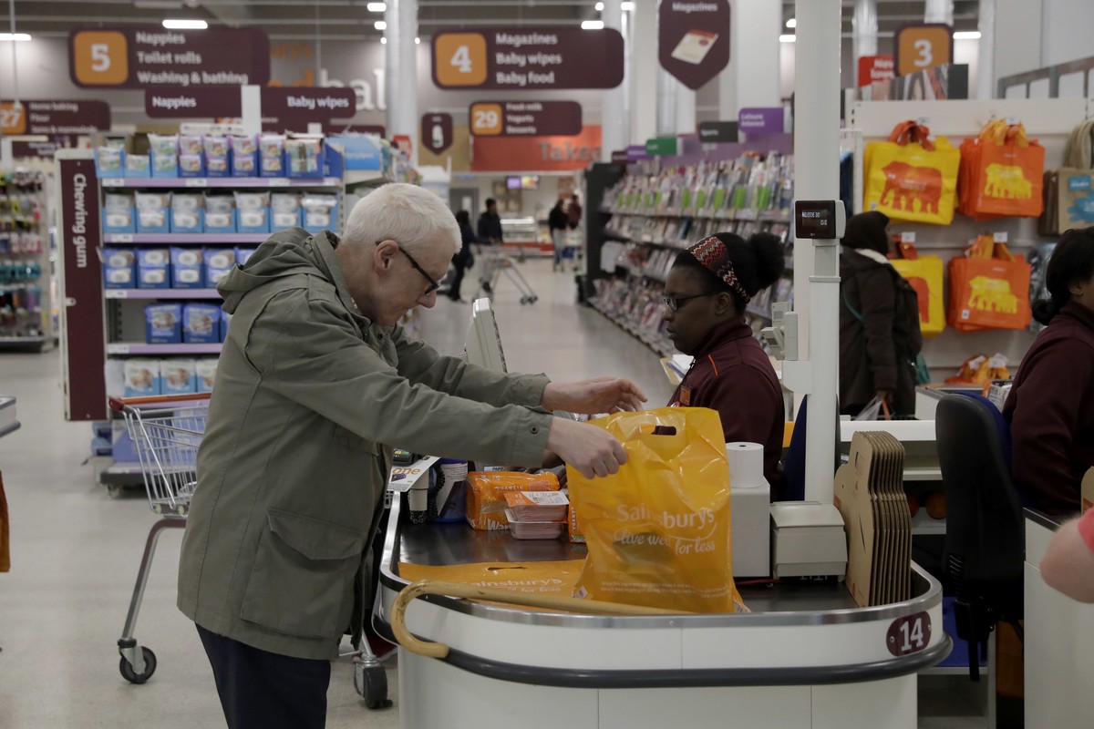 A customer buys shopping at a till in the Sainsbury's flagship store in the Nine Elms area of London, Monday, April 30, 2018. Sainsbury's has agreed to buy Walmart's U.K. unit, Asda, fo ...