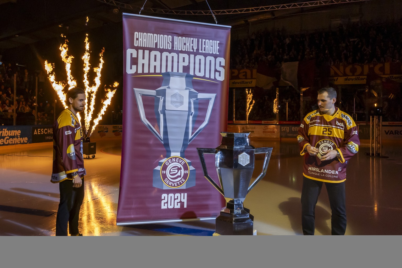 The commemorative banner of Champions Hockey league 2024 title is lifted next to Noah Rod (GSHC), left, and Roger Karrer (GSHC), right, prior a National League regular season game of the Swiss Champio ...