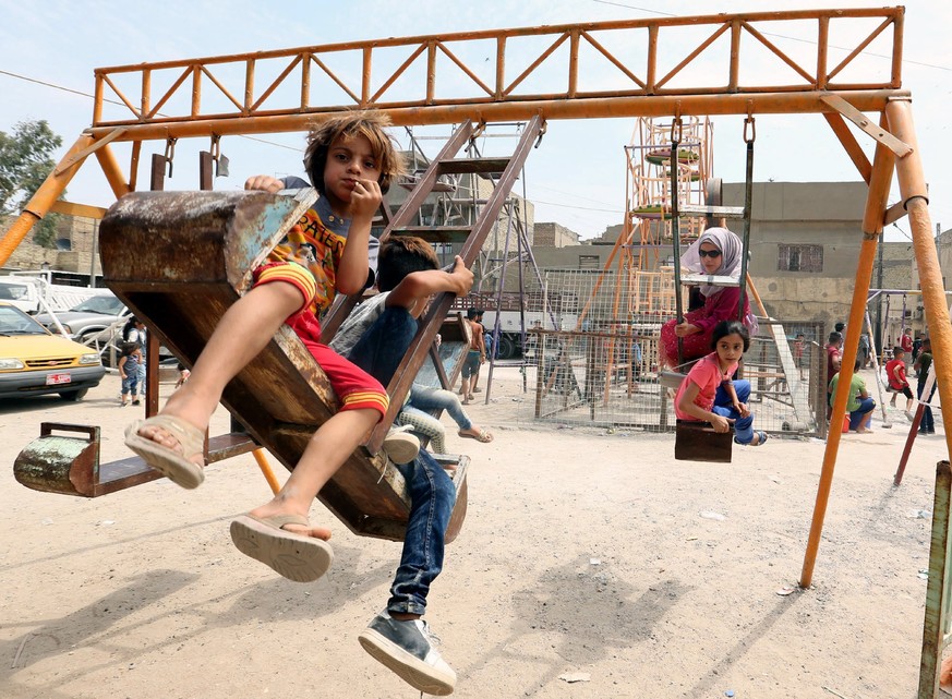 epa06181013 Iraqis children play on a swing during Eid al-Adha celebrations at a popular amusement park in central Baghdad, Iraq, 03 September 2017. Eid al-Adha is the holiest of the two Muslims holid ...