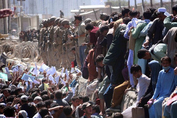 epa09430527 Afghans struggle to reach the foreign forces to show their credentials to flee the country outside the Hamid Karzai International Airport, in Kabul, Afghanistan, 26 August 2021. At least 1 ...