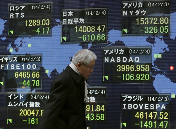 epa04054089 A businessman walks past figures of global stock markets displayed on an electric board during afternoon trade in Tokyo, Japan, 04 February 2014. The benchmark Nikkei 225 Stock Average dip ...