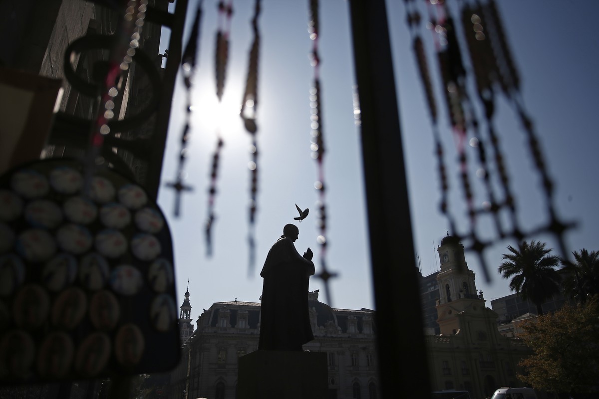 A pigeon flies over the statue of Cardinal Jose Maria Caro, in front of the Santiago Cathedral, in Santiago, Chile, Friday, May 18, 2018. In the biggest shake-up yet in the Catholic Church's long ...