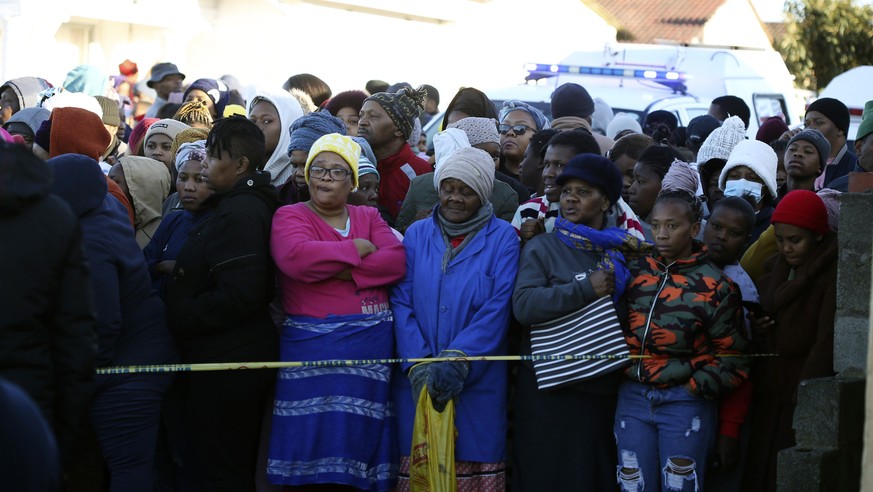 People stand behind a police cordon outside a nightclub in East London, South Africa, Sunday June 26, 2022. South African police are investigating the deaths of at least 20 people at a nightclub in th ...