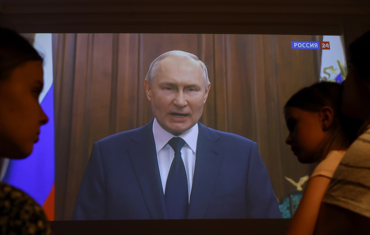 epa10712844 Members of a family watch Russian President Vladimir Putin's video address to the Nation on a tv screen, in Moscow, Russia, 26 June 2023. The Russian President on 26 June evening made ...