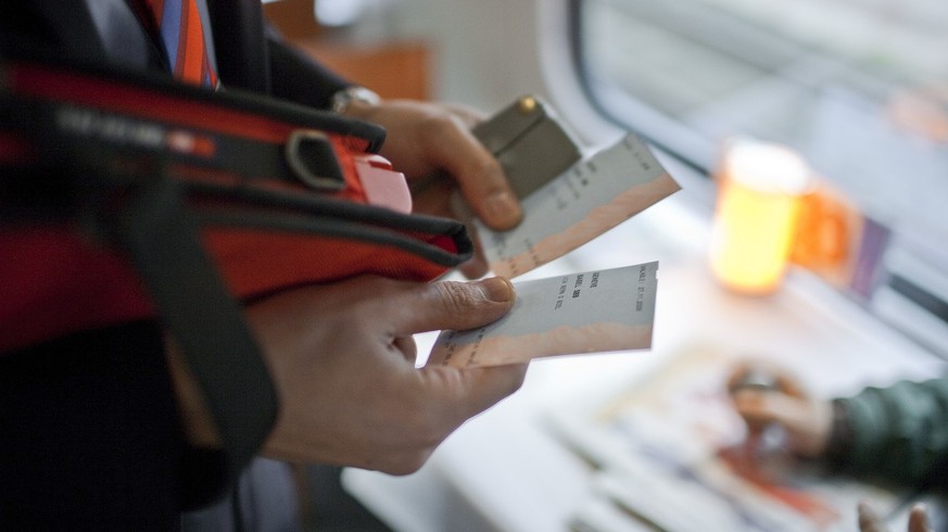 A ticket collector punches two tickets in an InterCity train of the Swiss Federal Railways SBB from Berne to Biel, Switzerland, on November 27, 2009. (KEYSTONE/Gaetan Bally) 

Ein Kondukteur kontrolli ...