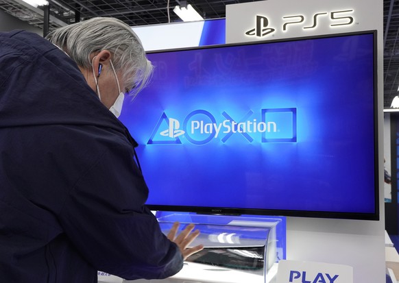 epa08814966 A man looks at the new Sony PlayStation 5 (PS5) console installed inside a plastic case at a discount chain store in Tokyo, Japan, 12 November 2020. Sony Interactive Entertainment Inc. lau ...