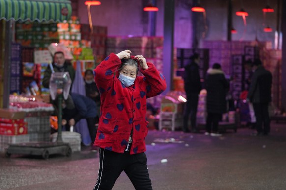 A woman wearing her mask walks past a fruit market near the Huanan Seafood Market in Wuhan, China, Sunday, Jan. 31, 2021. Scientists initially suspected the coronavirus came from wild animals sold in  ...