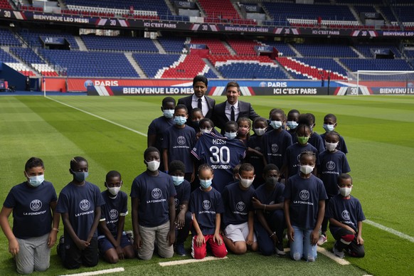 Surrounded by children, Lionel Messi, center right, and PSG president Nasser Al-Al-Khelaifi hold Messi's jersey Wednesday, Aug. 11, 2021 at the Parc des Princes stadium in Paris. Lionel Messi sai ...