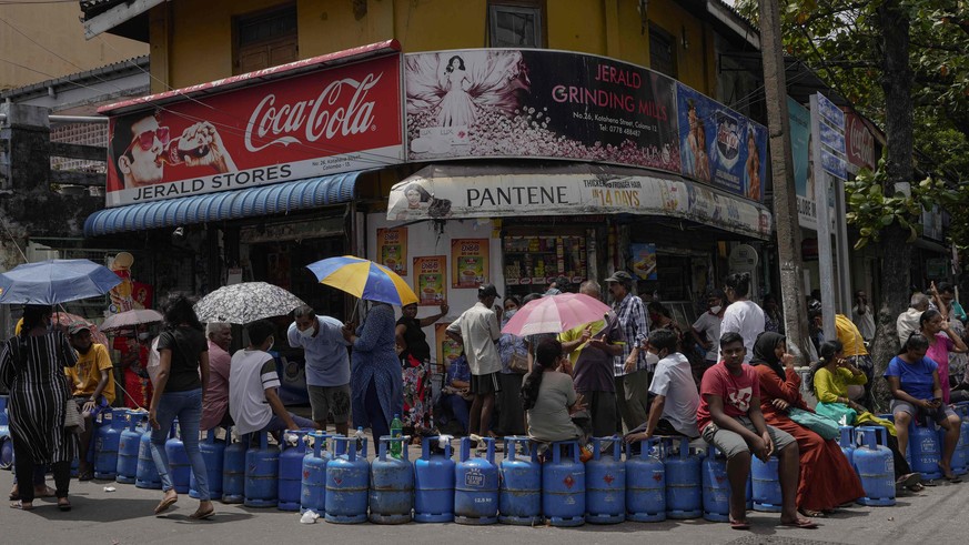 People wait in a queue expecting to buy cooking gas near a distribution center in Colombo, Sri Lanka, Tuesday, July 12, 2022. Facing severe shortages of food, fuel and medicine, protesters on Saturday ...
