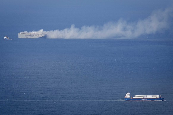 epa10770009 A cargo ship passes the Fremantle Highway that is on fire in the North Sea north of Ameland, the Netherlands, 26 July 2023. A fire broke out overnight on 26 July on the Fremantle Highway,  ...