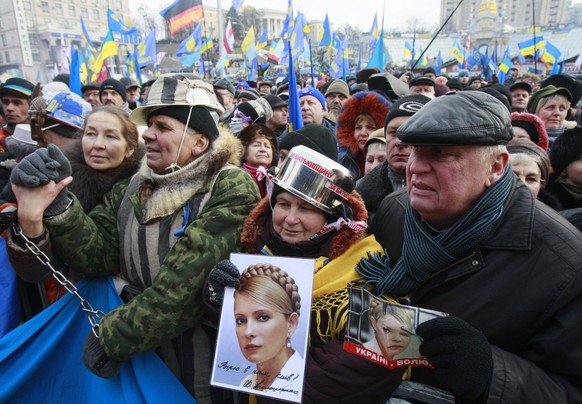 Die neuen Demonstrationsgesetze verbieten das Tragen schützender Kopfbedeckungen wie Helme und anderem. Diese Demonstranten helfen sich am 18. Januar 2014 im Stadtzentrum mit Kochtöpfen und halten Bil ...