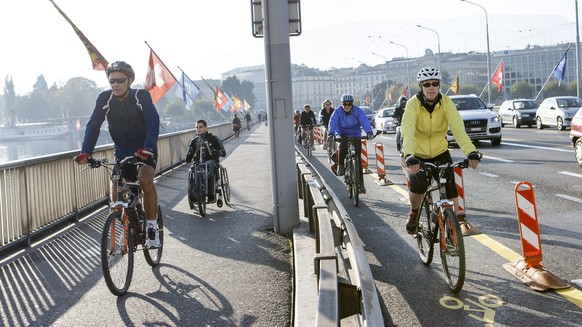 Des cyclistes roulent sur la piste cyclable du pont du Mont-Blanc alors qu&#039;un cycliste prefere rouler sur le trottoir, ce dimanche 15 octobre 2017 a Geneve. Le canton et la Ville de Geneve ont de ...