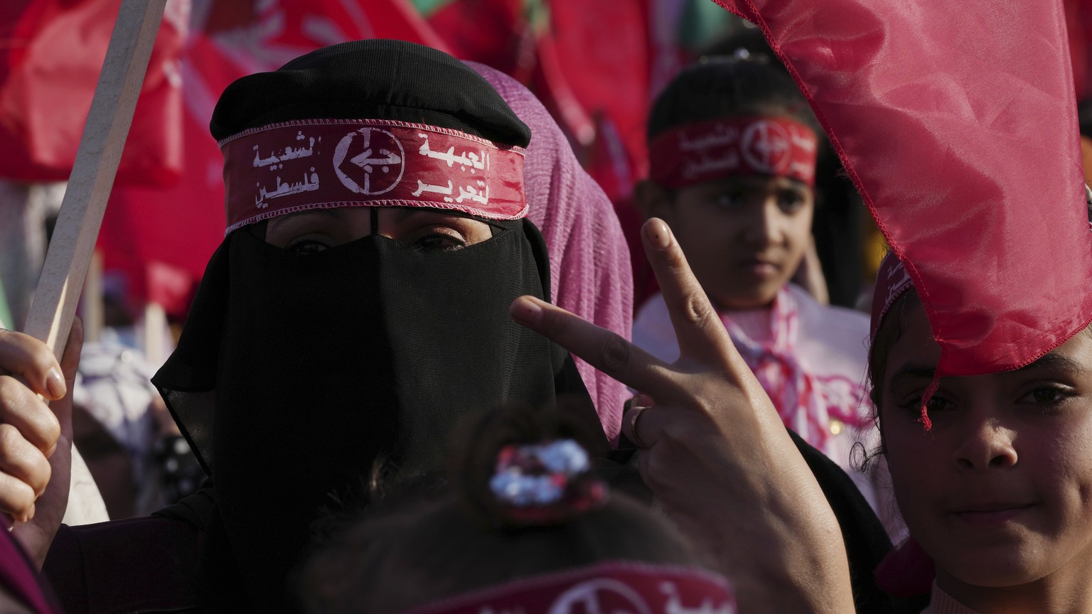 A veiled woman activist from the the Popular Front for the Liberation of Palestine (PFLP) waves her national and party&#039;s red flags while marking the 55th anniversary of the PFLP, at Al Kateba Squ ...