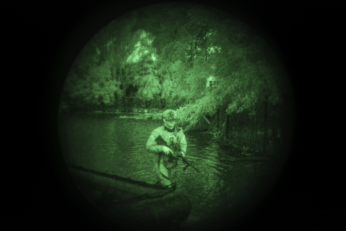 A Ukraine Special Operations Forces soldier walks through water on the shores of the Dnipro River using night vision goggles, or NVG, during a night mission in Kherson region, Ukraine, Sunday, June 11 ...
