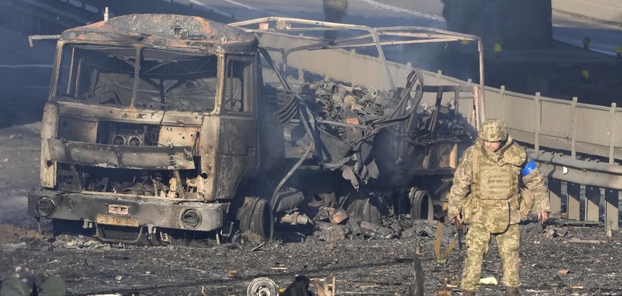 A Ukrainian soldier walks past the rubble of a burning military truck on a street in Kiev, Ukraine, Saturday, February 26, 2022. Russian troops stormed Ukraine's capital on Saturday, and street fighting...