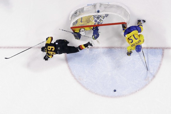 David Wolf (89), of Germany, collides with goalie Jhonas Enroth (1), of Sweden, and Simon Bertilsson (15), of Sweden, during the third period of a preliminary round men&#039;s hockey game at the 2018  ...