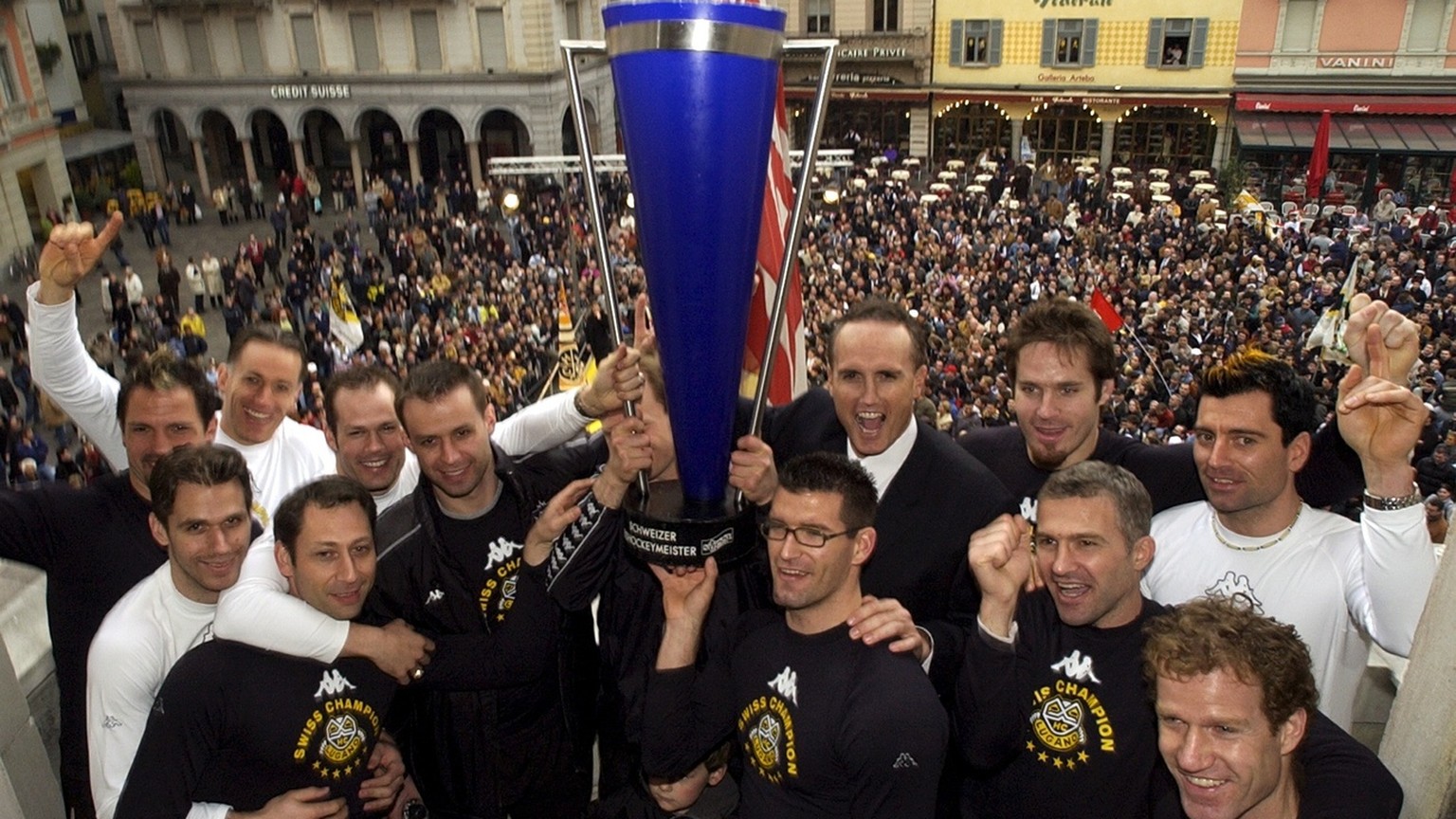 Spieler des HC Lugano und Trainer Larry Huras, hinten rechts neben dem Pokal, feiern am Freitag, 11. April 2003, mit dem Meisterpokal auf der Terrasse des Luganeser Rathauses den Meistertitel. Der HC  ...