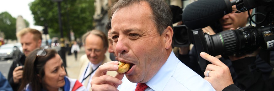epa06801922 Leave.EU Brexit campaign co-founder Arron Banks (R) eats a pie on his arrival to face questions by members of the British Parliament, Digital, Culture, Media and Sport committee, at Portcu ...