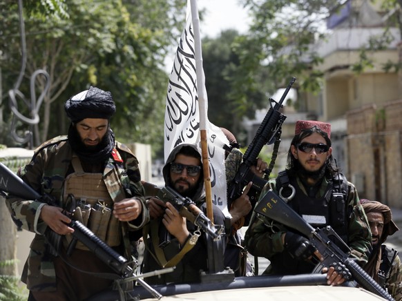 FILE - In this Aug. 19, 2021 file photo, Taliban fighters display their flag on patrol in Kabul, Afghanistan. The Taliban win in Afghanistan is giving a boost to militants in neighboring Pakistan. The ...