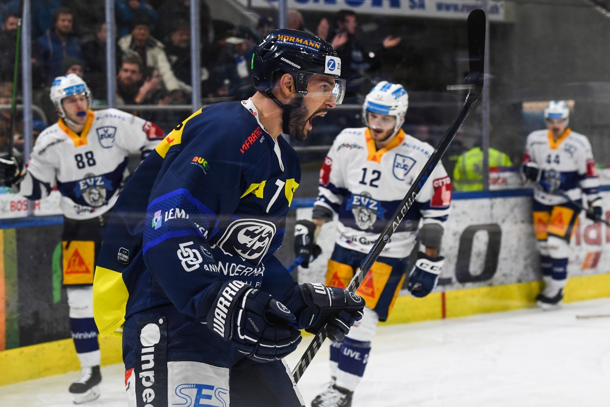 From left, Ambri's player Isacco Dotti celebrates the 1-1 goal next to Zug's player Sven Senteler, right, during the match of National League Swiss Championship 2022/23 between HC Ambri Piot ...