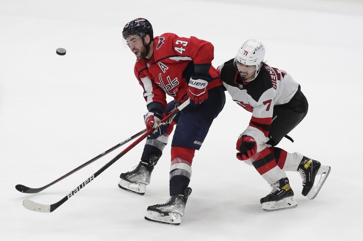 Washington Capitals' Tom Wilson (43) and New Jersey Devils' Jonas Siegenthaler (71) battle for the puck during the third period of an NHL hockey game, Sunday, Jan. 2, 2022, in Washington. (A ...