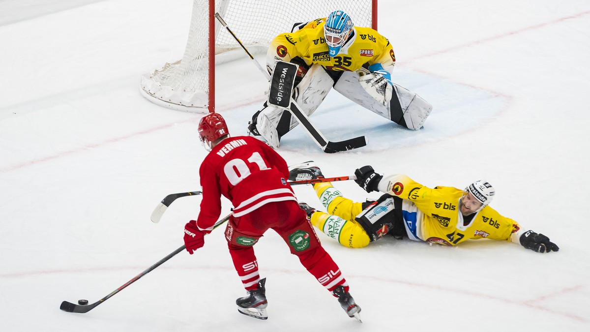 L'attaquant lausannois Joel Vermin, gauche, lutte pour le puck avec le gardien bernois Tomi Karhunen, centre, et le defenseur bernois Andrew MacDonald, droite, lors de la rencontre du championnat ...