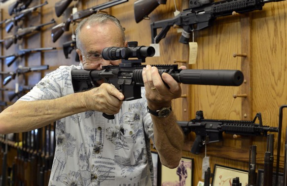 epa07855608 (FILE) - Vendor Jack Riddle looks through the scope while showing a Colt AR-15 rifle to customers at Chuck&#039;s Firearms gun store in Atlanta, Georgia USA, 27 July 2012 (reissued 20 Sept ...