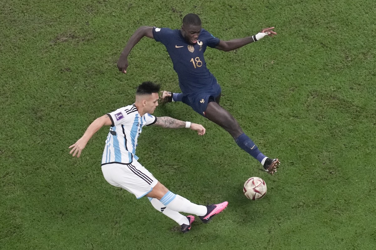 Argentina's Lautaro Martinez shoots on goal as France's Dayot Upamecano tries to block the shot during the World Cup final soccer match between Argentina and France at the Lusail Stadium in  ...