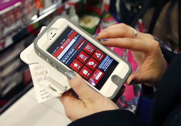 FILE - In this Friday, Nov. 23, 2012, file photo, Tashalee Rodriguez, of Boston, uses a smartphone app while shopping at Macy&#039;s in downtown Boston. Shoppers are flocking online Monday, Nov. 28, 2 ...