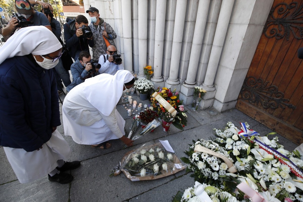 epa08785304 Nuns lay flowers on a makeshift memorial to the victims of the knife attack at the entrance of the Notre Dame Basilica church in Nice, France, 30 October 2020. Three people have died in a  ...