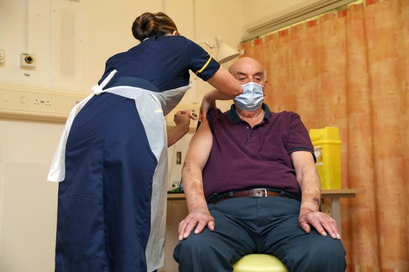 82-year-old Brian Pinker receives the Oxford University/AstraZeneca COVID-19 vaccine from nurse Sam Foster at the Churchill Hospital in Oxford, England, Monday, Jan. 4, 2021. Pinker, a retired mainten ...