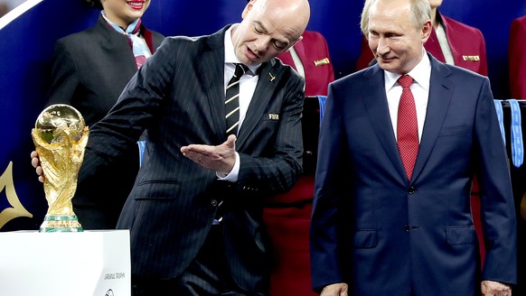 epa06891798 Russian President Vladimir Putin (R) and FIFA president Gianni Infantino react next to the FIFA World Cup 2018 trophy after the FIFA World Cup 2018 final between France and Croatia in Mosc ...