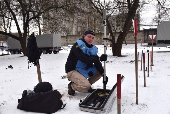 Dmijtro prepares his equipment next to a field of practice mines.