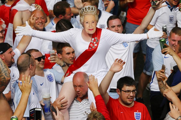 Football Soccer - EURO 2016 - Saint Etienne, France - 20/6/16 - An female England fan wears a mask of Queen Elizabeth II as she rides on the shoulders of her mates gathering in Saint Etienne ahead of  ...