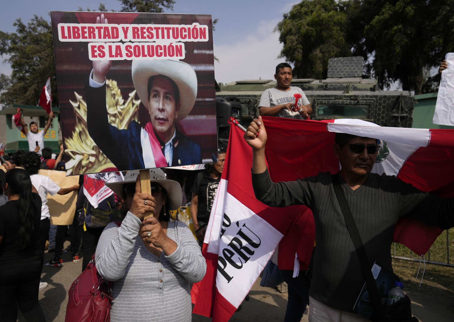 Supporters of former President Pedro Castillo gather outside the police base where he is being held following his arrest and faces charges of rebellion on the outskirts of Lima, Peru, Wednesday, Dec.  ...